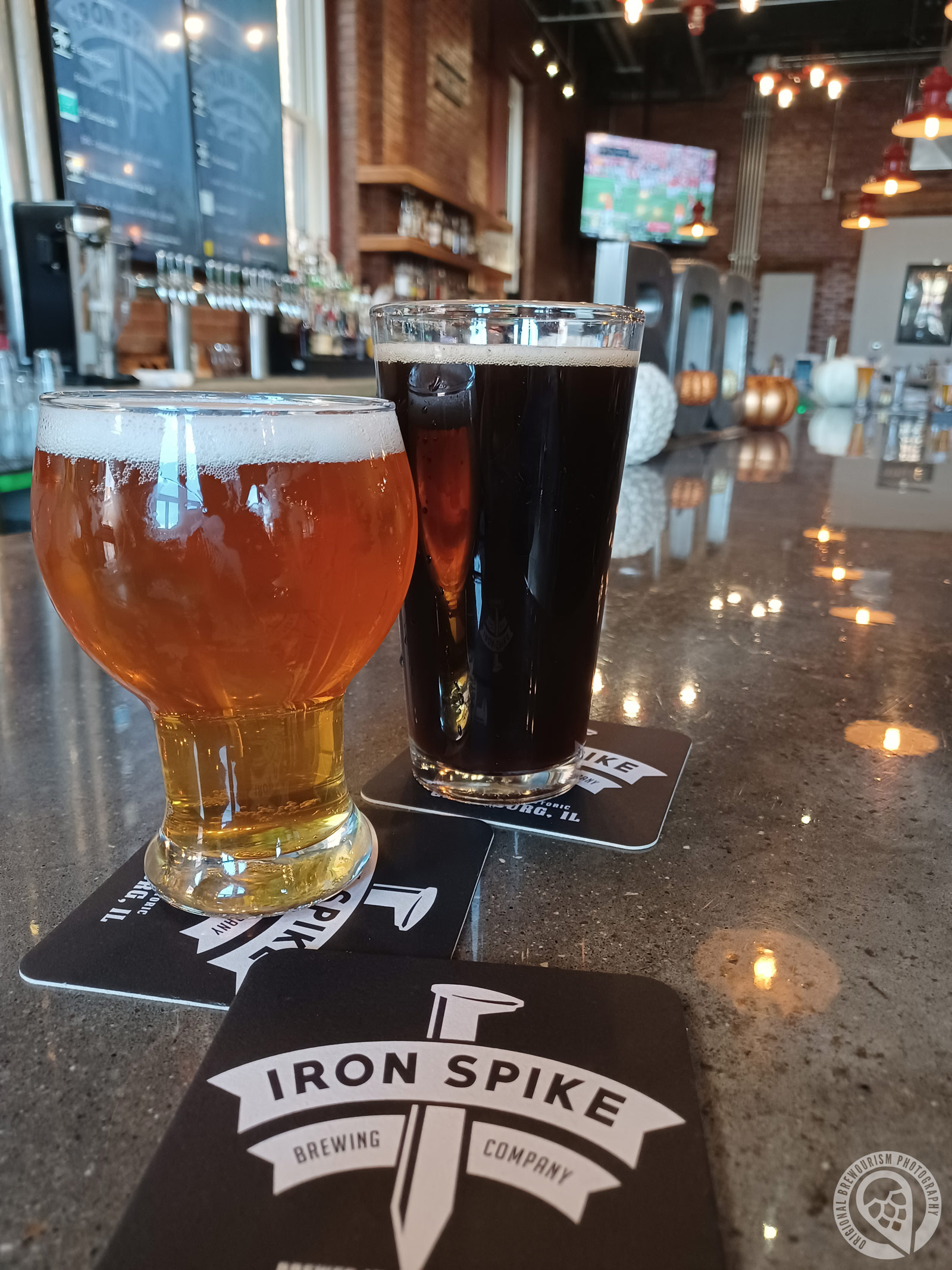 Two pints of beer on the bar with coaster from Iron Spike Brewery
